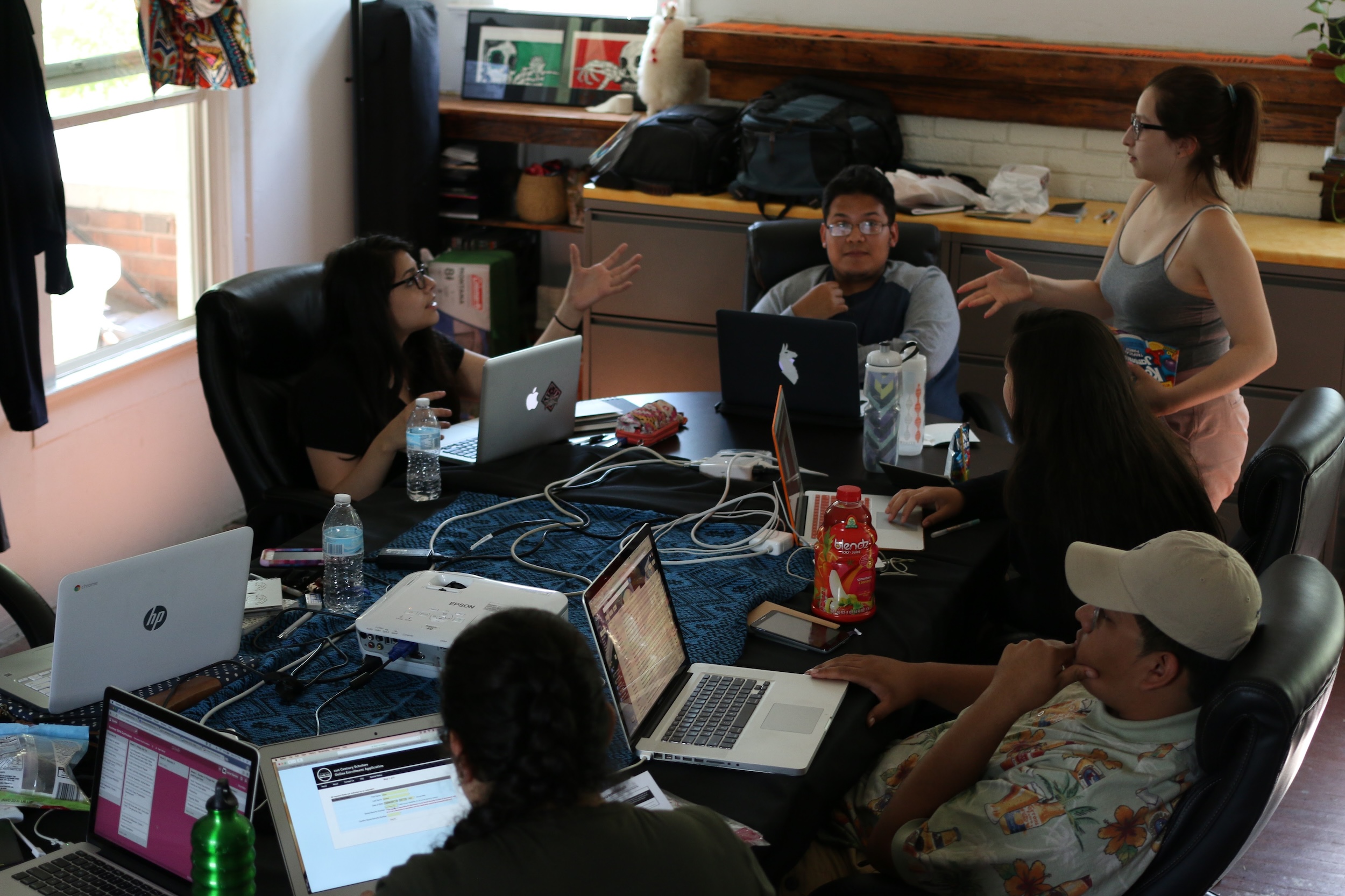 Athena Academy scholars collaborating on laptops around a table during the summer program